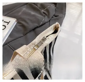 Close-up of smooth silver metal zipper on black and white striped canvas bag