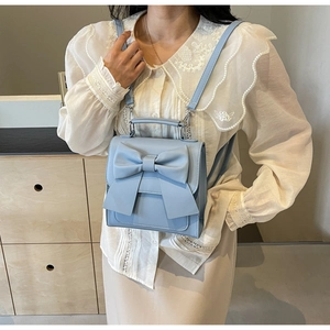 Detail of light blue mini backpack with a large bow showing soft PU leather texture