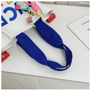 Détail de l'anse du sac en toile avec charms sportifs colorés et sangles bleues contrastées