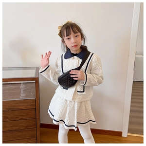 Detail of a child wearing a black quilted diamond pattern waist bag with a collegiate outfit