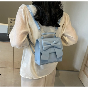 Back view of light blue mini backpack with decorative bow knot on female model