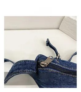 Detailed close-up of smooth silver metal zipper and white stitching on denim bag