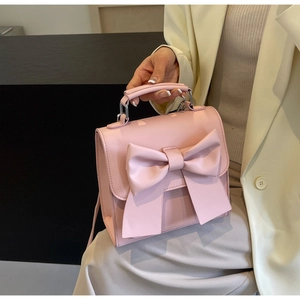 Detail of pink mini handbag featuring a large bow and premium leather texture