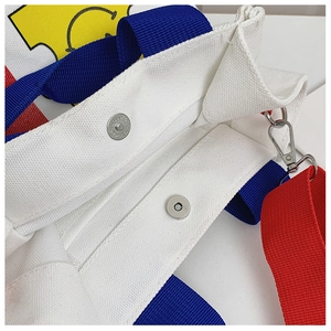 Détail macro du sac cabas en toile blanche avec boucle magnétique et poignée en ruban bleu