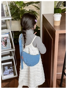 Detailed back view of a child wearing the stylish blue denim half-moon crossbody bag