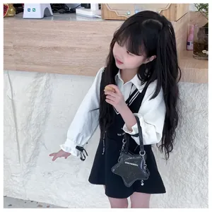 Fille en chemisier blanc et robe noire portant le sac à bandoulière en forme d'étoile