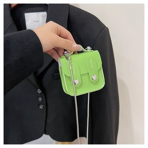 Détail d'un mini sac à bandoulière vert fluo avec chaîne argentée et boucles métal