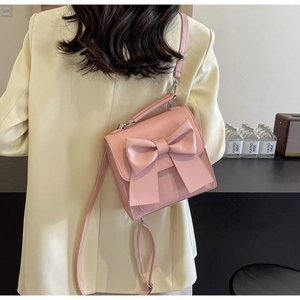Detailed view of a pink PU leather mini bag with a large bow on a model's back