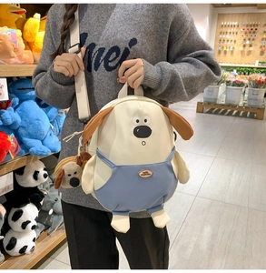 Dettaglio dello zaino a forma di cane in tela con decorazione blu e ciondolo di peluche