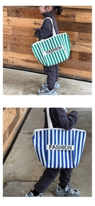 Close-up of striped canvas tote bags in green and blue with FASHION letter strap details