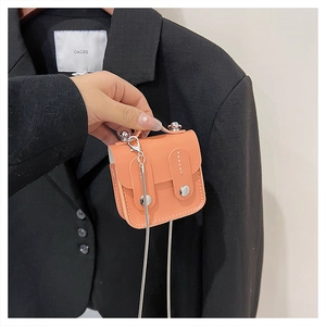 Détail d'un mini sac à bandoulière orange vif avec boucle argentée et bandoulière chaîne
