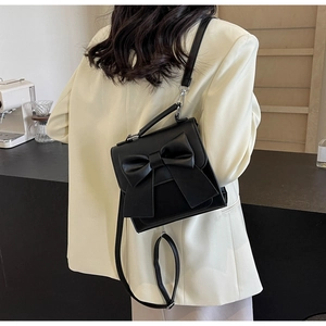 Model view of a black mini backpack with a large bow detail and adjustable shoulder straps