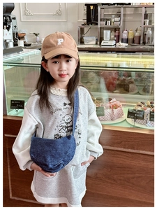 Detail view of a child wearing a dark blue denim half-moon crossbody bag in a real-life setting