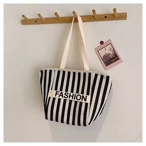 Close-up of striped canvas crossbody bag with FASHION text on a wooden hanger