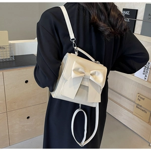 Elegant beige PU leather backpack featuring a large decorative bow and versatile straps