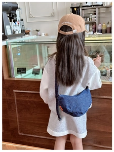 Detail of dark blue denim dumpling bag and khaki baseball cap in a cafe scene