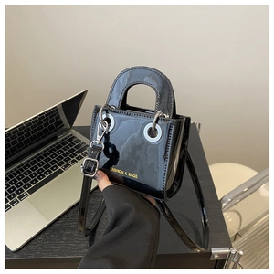 Détail du mini sac en cuir verni noir brillant avec œillets argentés et texte gravé