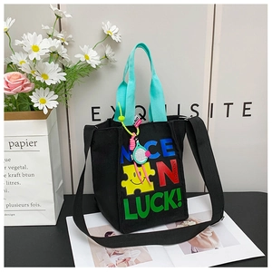 Détail du sac cabas en toile noire avec des lettres colorées et un motif de smiley jaune