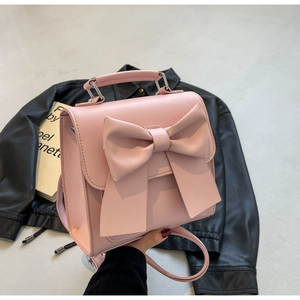 Detail of a pink mini backpack with a large bow decoration and matte leather finish