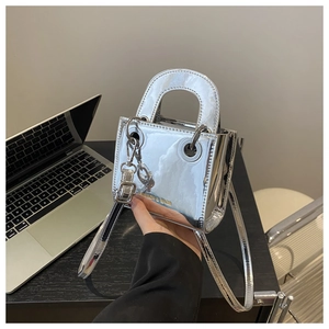 Sac carré en cuir verni argenté pour enfants avec poignée en métal sur bureau