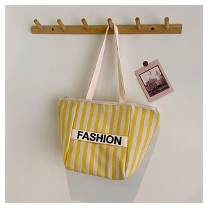 Detail of yellow and white striped canvas tote bag with FASHION letter webbing
