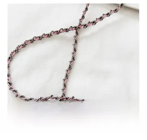 Detail showing high-quality dark metal chain interwoven with soft pink leather strap