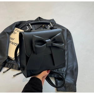 Detail of black mini backpack featuring a large fashion bow and silver metal handle hardware