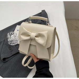 Detailed close-up of a cream white mini crossbody bag with a large decorative bow