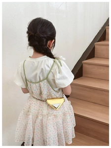 Detail of a kids gold metallic triangle chain bag on a floral layered dress outfit
