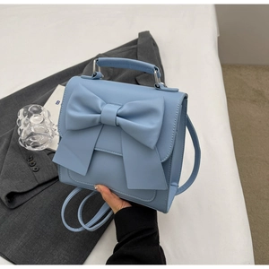 Macro shot of light blue mini handbag with oversized bow detail and a thin strap