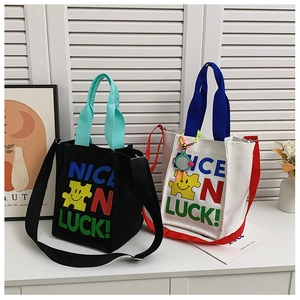 Détail du sac bandoulière en toile bicolore avec imprimé Nice Luck et motif smiley