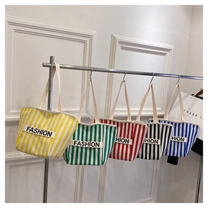 Detailed view of striped canvas tote bags with 'FASHION' label and shoulder straps