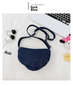 Detail view of deep blue denim dumpling bag with adjustable strap and metal buckle