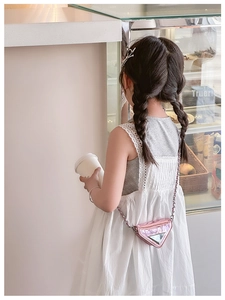 Pink metallic triangle mini bag with silver chain strap shown in a lifestyle bakery setting