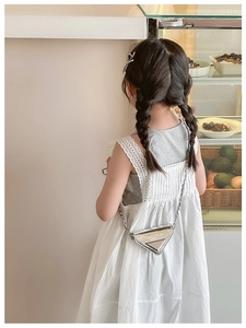 Detail of silver metallic triangle mini bag with chain strap on white lace dress