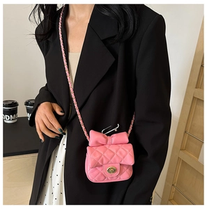 Detail of pink quilted crossbody bag for kids featuring a large bow and gold twist lock