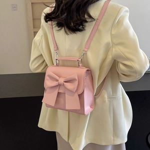 Pink mini backpack with bow decoration shown on model in light yellow suit