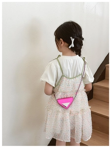 Detail of pink laser patent leather mini bag with chain strap worn by a young girl