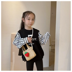 Detailed view of child wearing straw crossbody bag with strawberry and striped sweatshirt