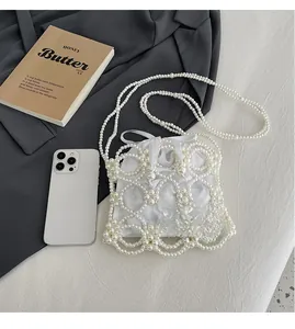 Détail du sac seau en perles blanches avec doublure en satin sur fond gris texturé