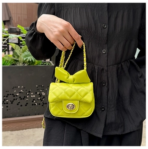 Close-up of bright green quilted crossbody bag with bow detail and gold chain strap