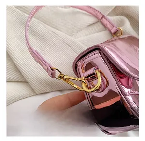 Close-up of metallic pink saddle bag featuring gold hardware clasps and precise stitching