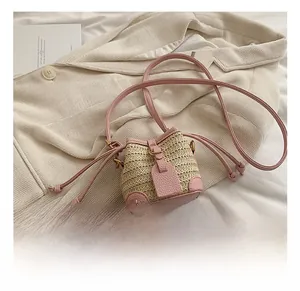 Détail de la bordure en cuir rose et fermeture à cordon sur mini sac seau en paille