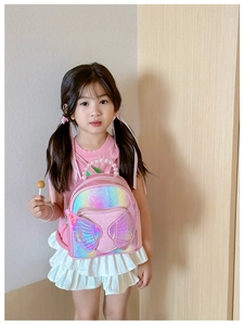 Pink sequin kids backpack with holographic wings and a pearl handle shown on a child