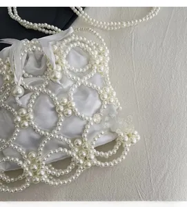 Détail du sac seau en perles tressées avec pochette intérieure en satin blanc brillant