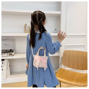 Hand-woven straw bag for girls with a pink bow and pearl accents on a young model