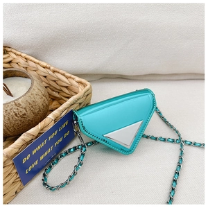 Close-up of a teal patent leather triangular mini bag with a woven silver chain strap