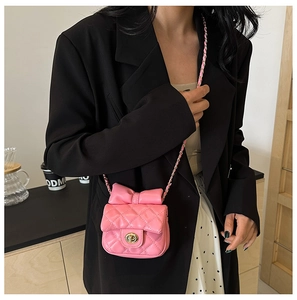 Close-up of pink quilted crossbody bag with bow decoration and gold chain strap