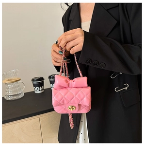 Close-up of pink quilted crossbody bag with a large bow detail and gold chain strap