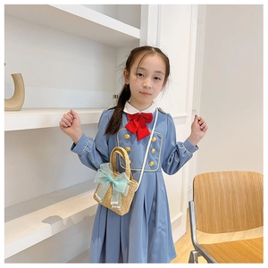 Detail of hand-woven straw handbag featuring a blue organza bow and pearl accents for girls